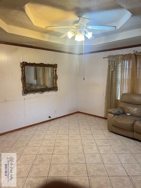 unfurnished room with a textured ceiling, a raised ceiling, ceiling fan, and light tile patterned flooring