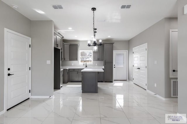 kitchen featuring pendant lighting, sink, gray cabinets, fridge, and a center island