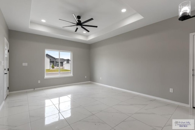 unfurnished room with a raised ceiling and ceiling fan