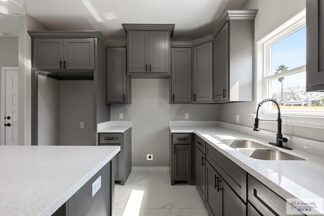 kitchen with sink, gray cabinets, and light stone countertops