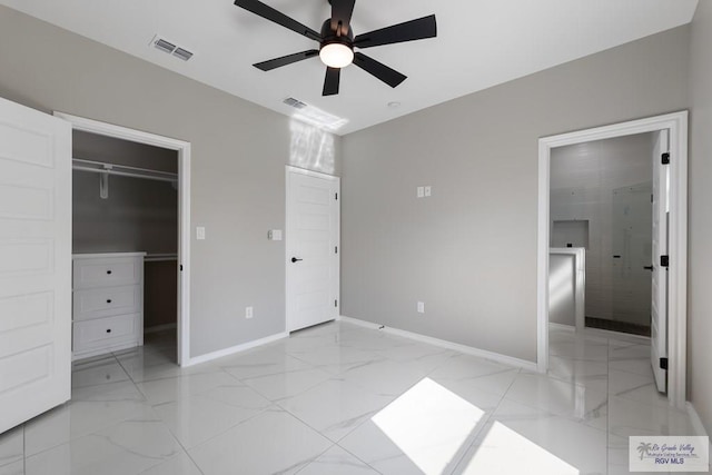 unfurnished bedroom featuring ceiling fan, ensuite bathroom, a spacious closet, and a closet