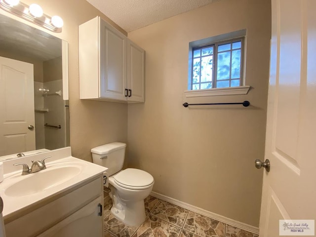 bathroom with a textured ceiling, vanity, and toilet