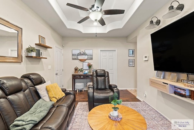 living room with hardwood / wood-style floors, a tray ceiling, and ceiling fan