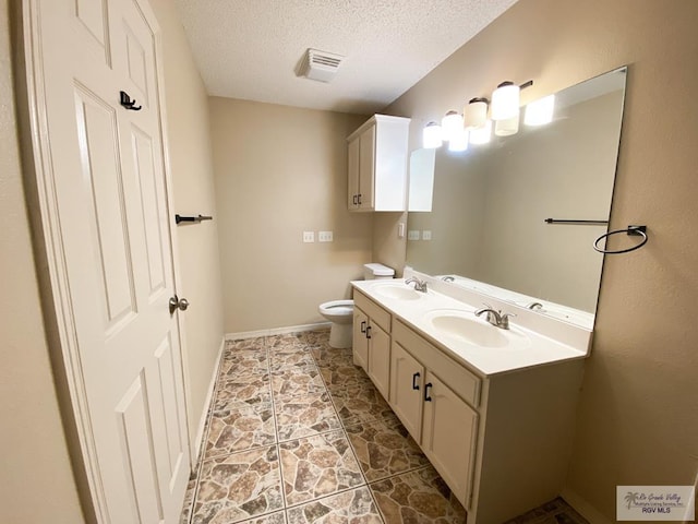 bathroom featuring vanity, toilet, and a textured ceiling