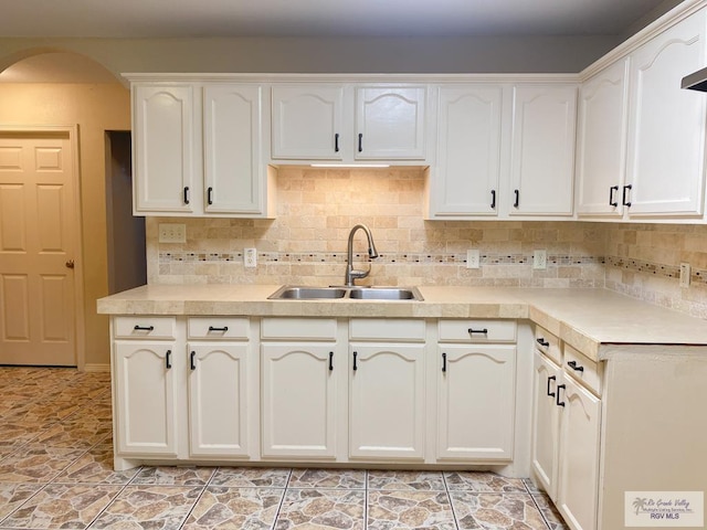 kitchen with decorative backsplash, sink, and white cabinets