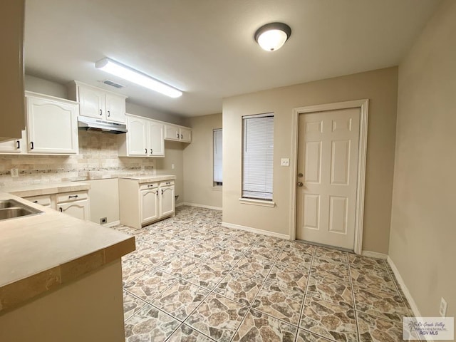 kitchen featuring backsplash, sink, and white cabinets