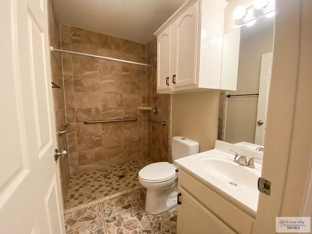 bathroom featuring vanity, a tile shower, a textured ceiling, and toilet