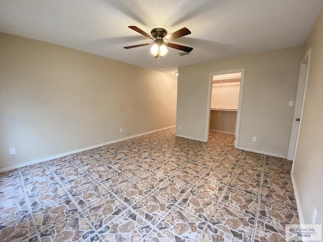 unfurnished bedroom with ceiling fan, a closet, a spacious closet, and a textured ceiling