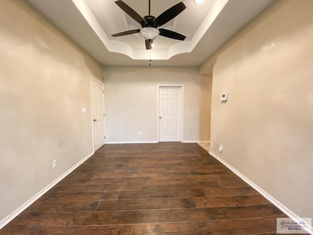 spare room featuring dark hardwood / wood-style floors, ceiling fan, and a raised ceiling