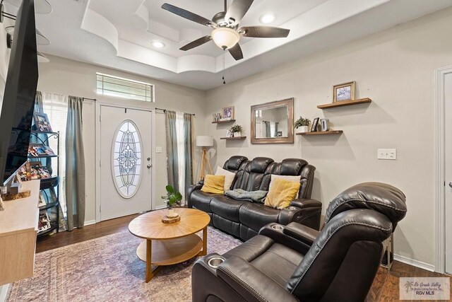 living room with a raised ceiling, ceiling fan, and hardwood / wood-style floors