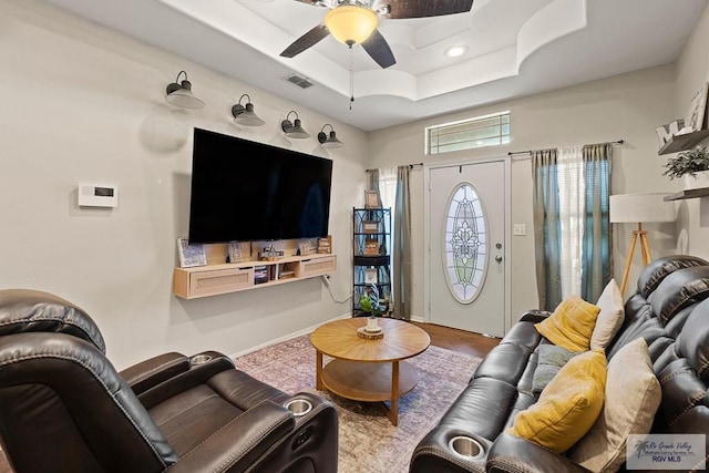 living room featuring a raised ceiling, ceiling fan, and hardwood / wood-style flooring