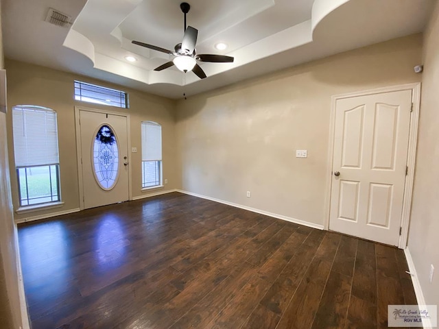 entrance foyer with a tray ceiling, ceiling fan, plenty of natural light, and dark wood-type flooring