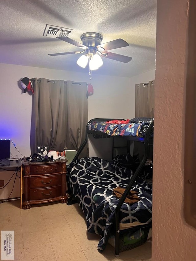 bedroom with a textured ceiling, visible vents, and a ceiling fan