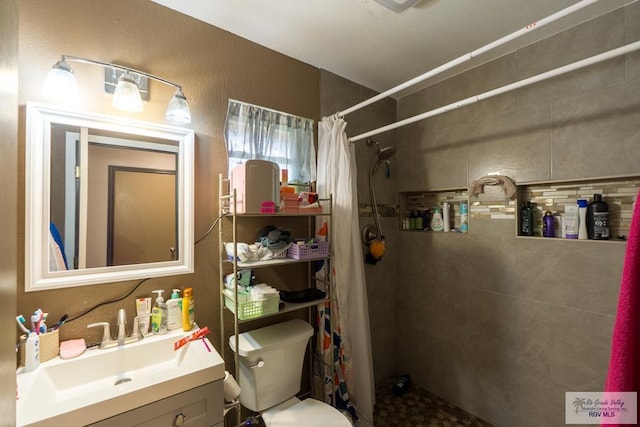 full bathroom featuring a tile shower, toilet, and vanity