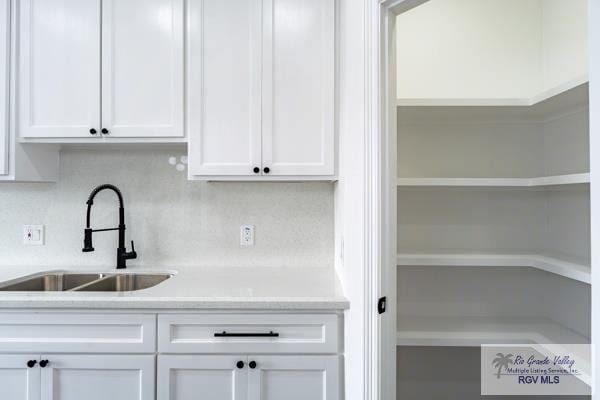 kitchen with backsplash, sink, and white cabinets