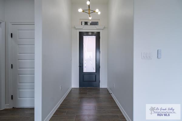 entryway with dark wood-type flooring and a notable chandelier