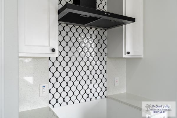 details featuring white cabinetry and wall chimney range hood