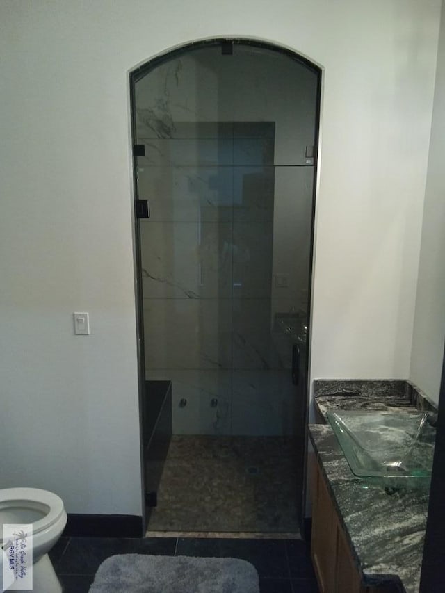 bathroom with vanity, a tile shower, tile patterned floors, and toilet