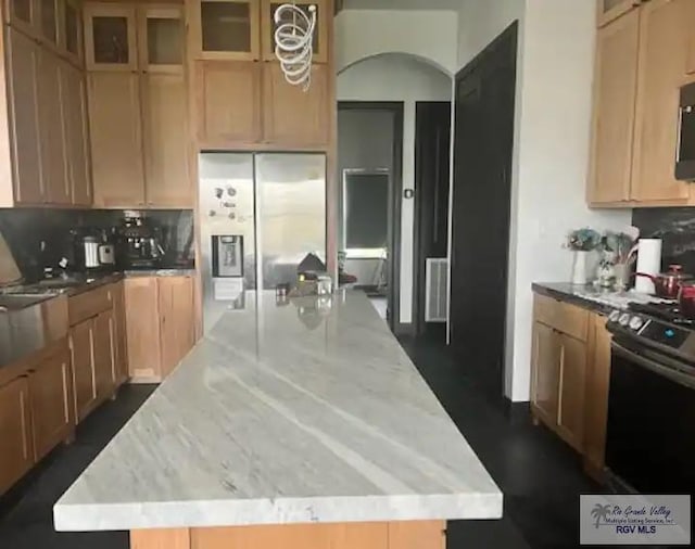 19 Laguna Madre Dr, Laguna Vista, TX 78578 - kitchen featuring glass insert cabinets, light stone counters, a kitchen island, backsplash, and stainless steel appliances