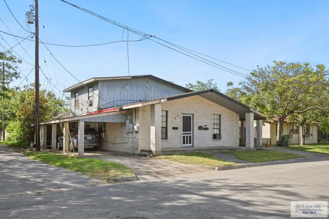 view of front of property with brick siding, a carport, and aphalt driveway