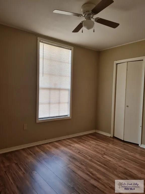 unfurnished bedroom with baseboards, a ceiling fan, wood finished floors, and a closet