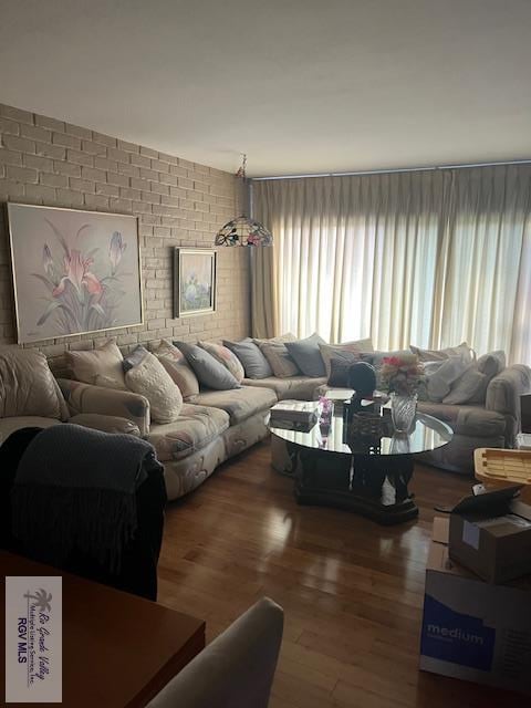 401 Boca Chica Blvd Unit 110, Brownsville, TX 78520 - living room featuring wood finished floors, plenty of natural light, and brick wall