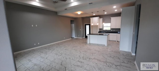 kitchen with pendant lighting, a center island, white cabinetry, and sink