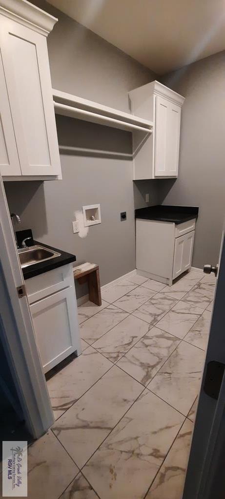 laundry area featuring electric dryer hookup, hookup for a washing machine, cabinets, and sink