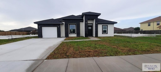 prairie-style home featuring a garage and a front lawn