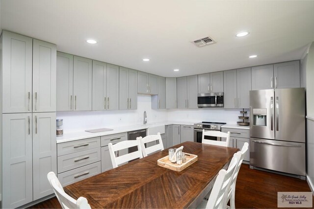 kitchen featuring appliances with stainless steel finishes, dark hardwood / wood-style floors, gray cabinetry, and sink