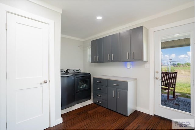 clothes washing area with washing machine and clothes dryer, crown molding, dark hardwood / wood-style flooring, and cabinets