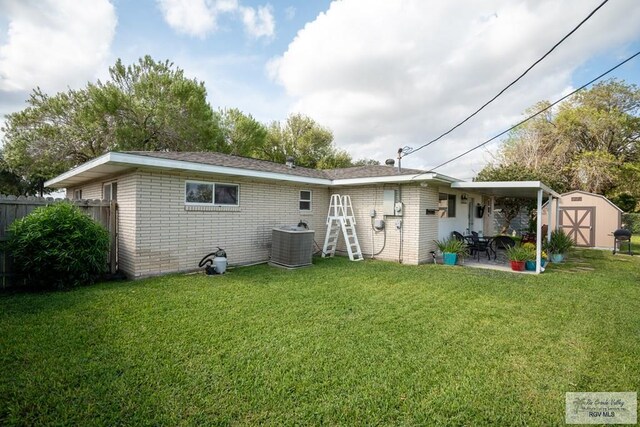 rear view of house with a patio, a yard, central AC, and a storage shed