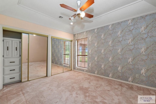 unfurnished bedroom with carpet floors, multiple closets, ceiling fan, and visible vents