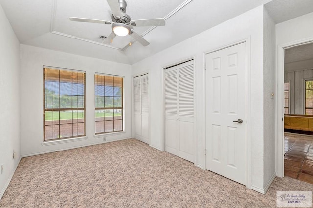 unfurnished bedroom featuring baseboards, ceiling fan, carpet flooring, and two closets