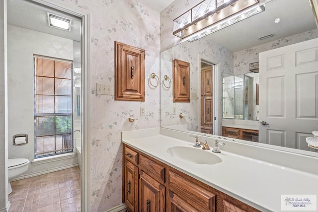 bathroom with vanity, baseboards, toilet, and wallpapered walls