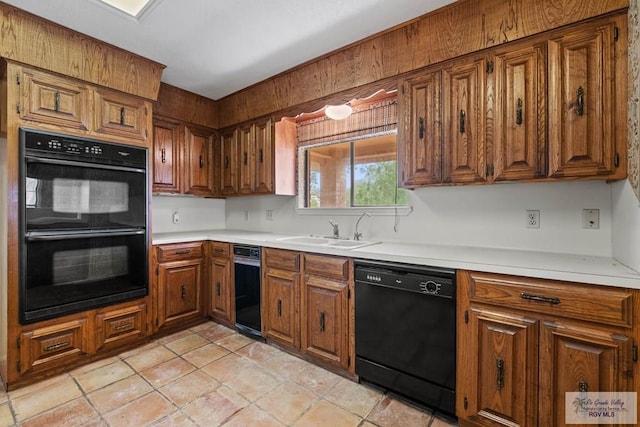 kitchen with a sink, light countertops, brown cabinetry, and black appliances