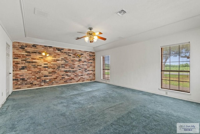 empty room featuring carpet floors, a ceiling fan, brick wall, and a wealth of natural light