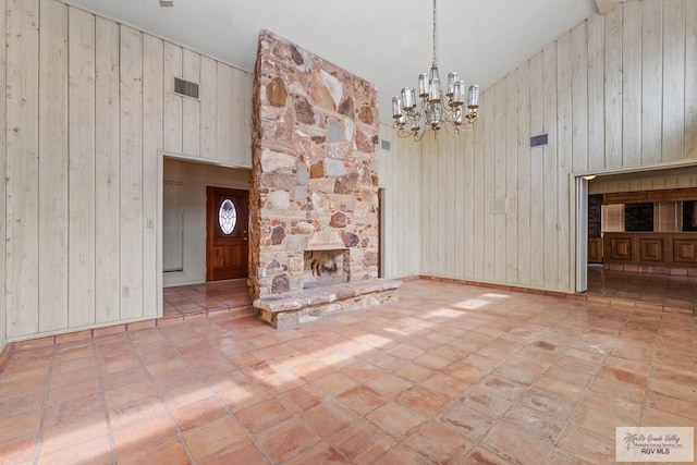 unfurnished living room featuring wood walls, a notable chandelier, and high vaulted ceiling