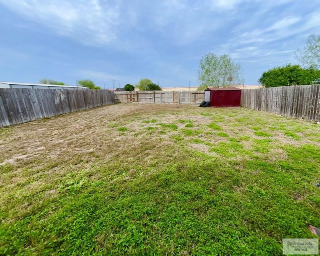 view of yard with an outbuilding, a shed, and a fenced backyard