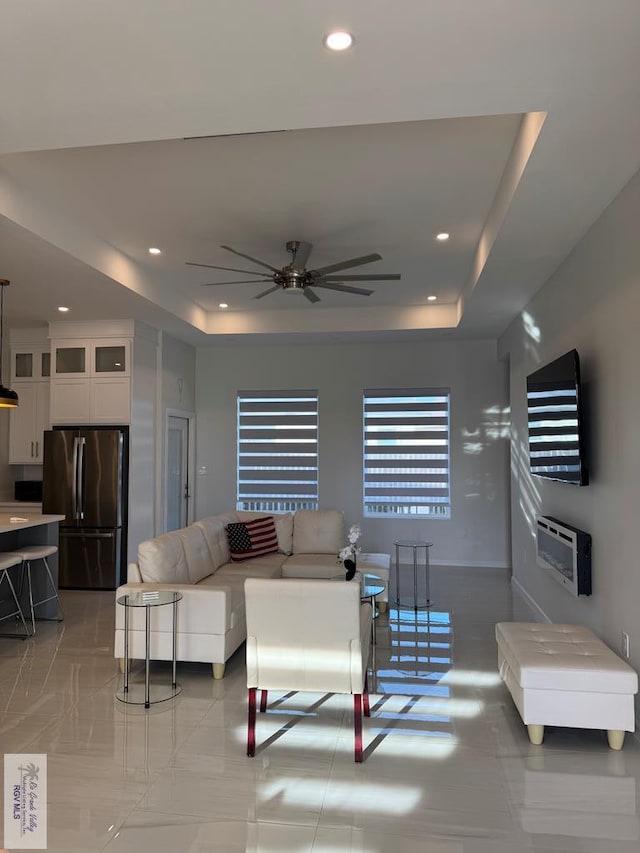 living room with a raised ceiling and ceiling fan