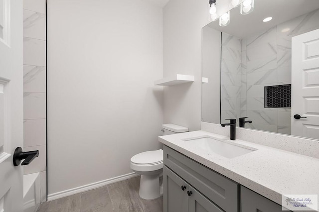 324 N Leon Ave, Elsa, TX 78543 - full bathroom featuring toilet, a shower, vanity, baseboards, and wood finished floors