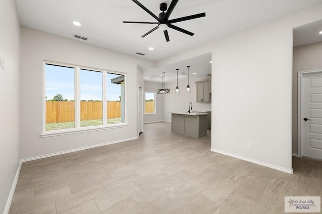 324 N Leon Ave, Elsa, TX 78543 - unfurnished living room featuring a ceiling fan, baseboards, a sink, and recessed lighting