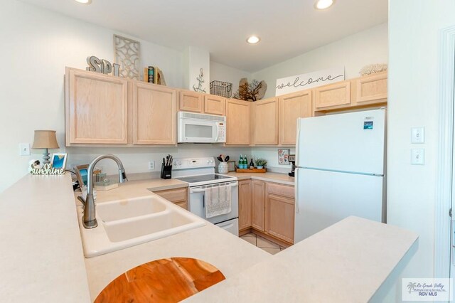 kitchen featuring kitchen peninsula, light brown cabinets, white appliances, and sink