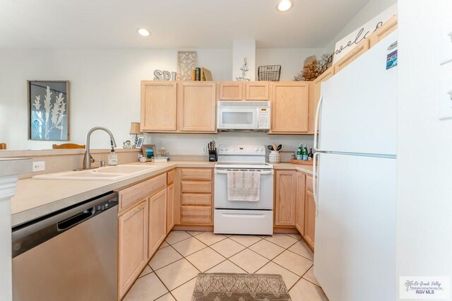 kitchen with light brown cabinets, white appliances, and sink