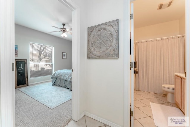 bedroom with ensuite bath, ceiling fan, and light tile patterned flooring