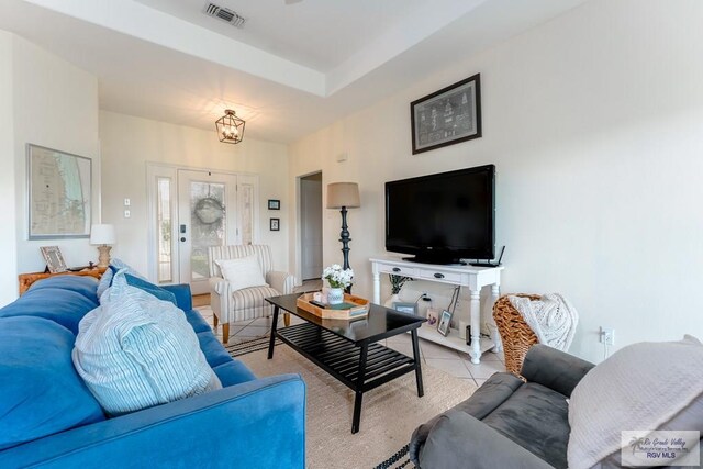 tiled living room featuring a notable chandelier