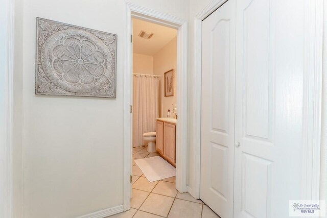 bathroom with toilet, vanity, and tile patterned floors