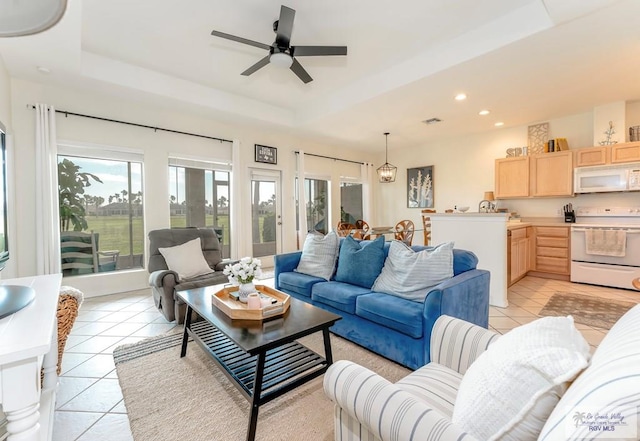 tiled living room with a tray ceiling and ceiling fan