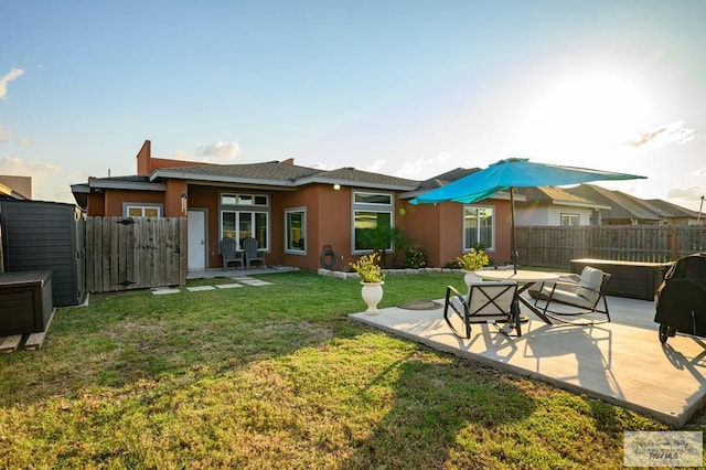 back of property featuring a lawn, a patio, and a hot tub