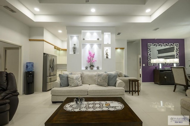 living room with light tile patterned floors and a tray ceiling